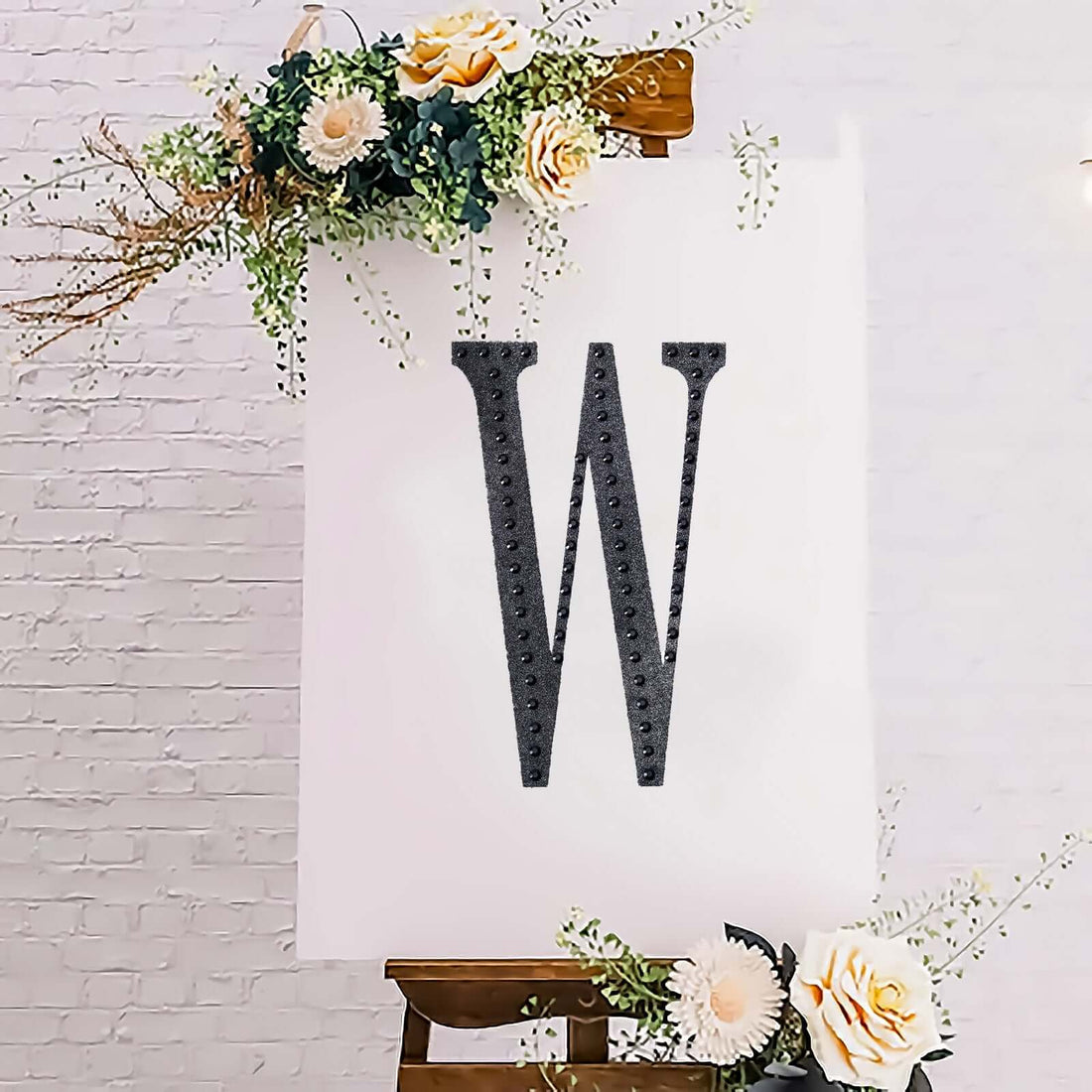 Decorative letter 'W' on an easel with floral accents.