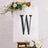 Decorative letter 'W' on an easel with floral accents.