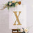 Gold marquee letter X on an easel with floral decorations.