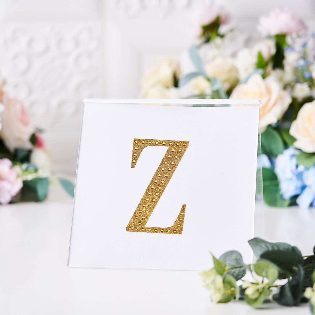 Gold letter Z on a decorative card with floral background.