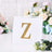 Gold letter Z on a decorative card with floral background.