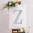 Decorative letter 'Z' on an easel with floral accents.