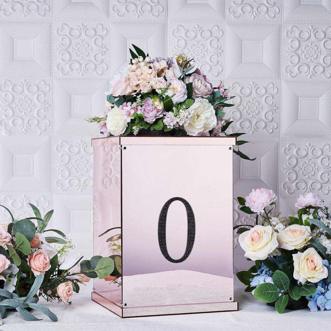 Rose gold floral arrangement box with number "0" on a textured background.