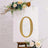 Gold decorative number zero on an easel with floral accents.