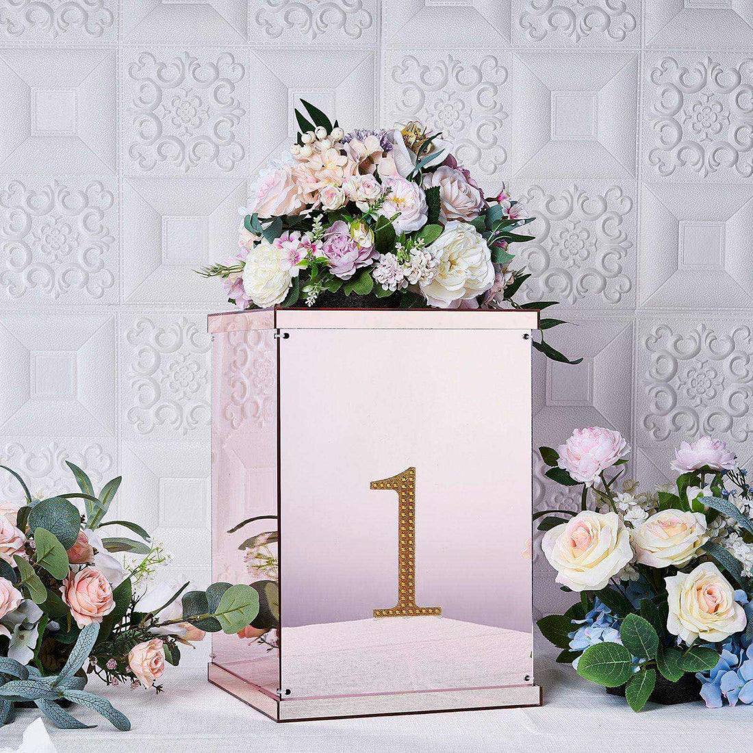 Rose gold number one display box with floral arrangement on a textured background.