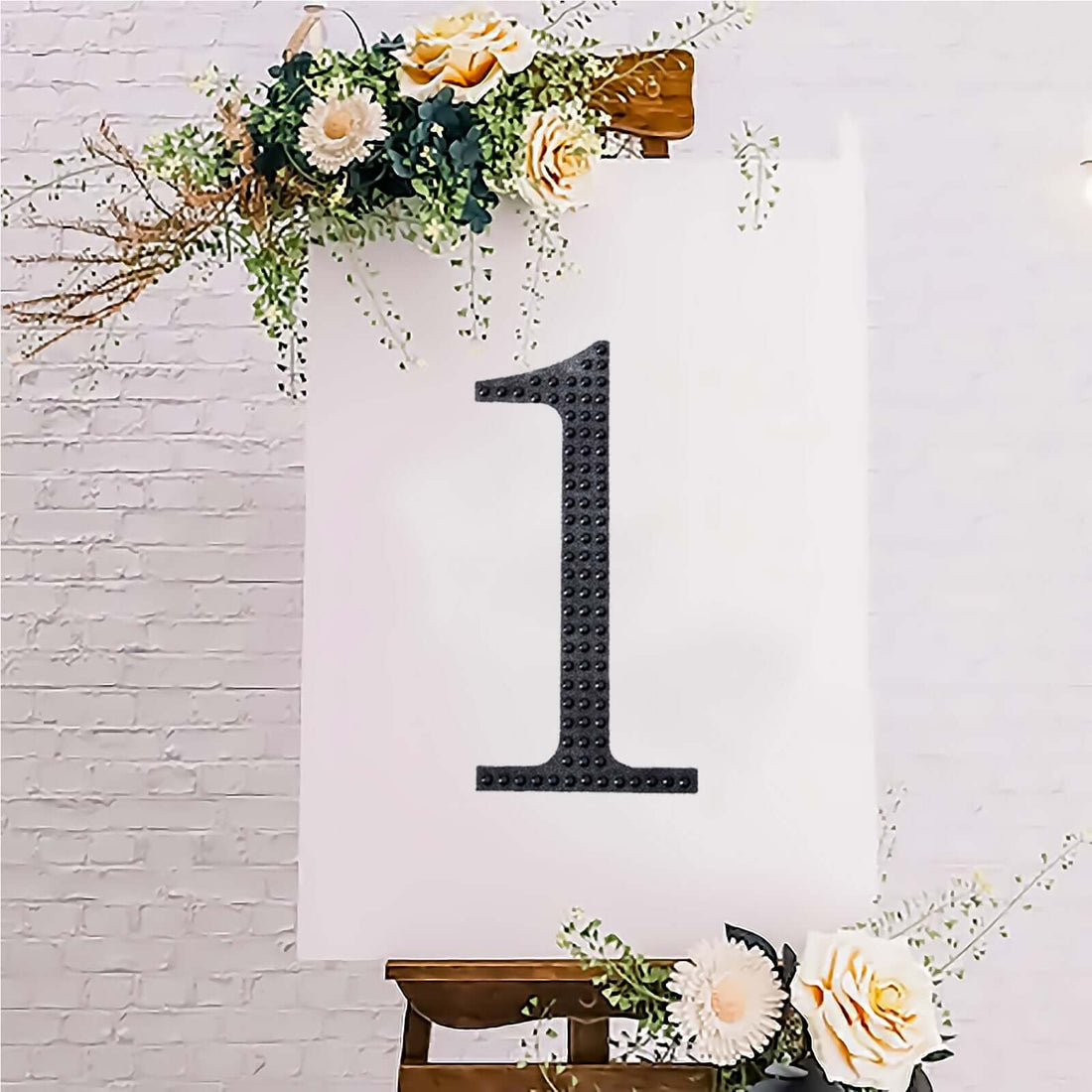 Decorative sign with number one surrounded by flowers on an easel.