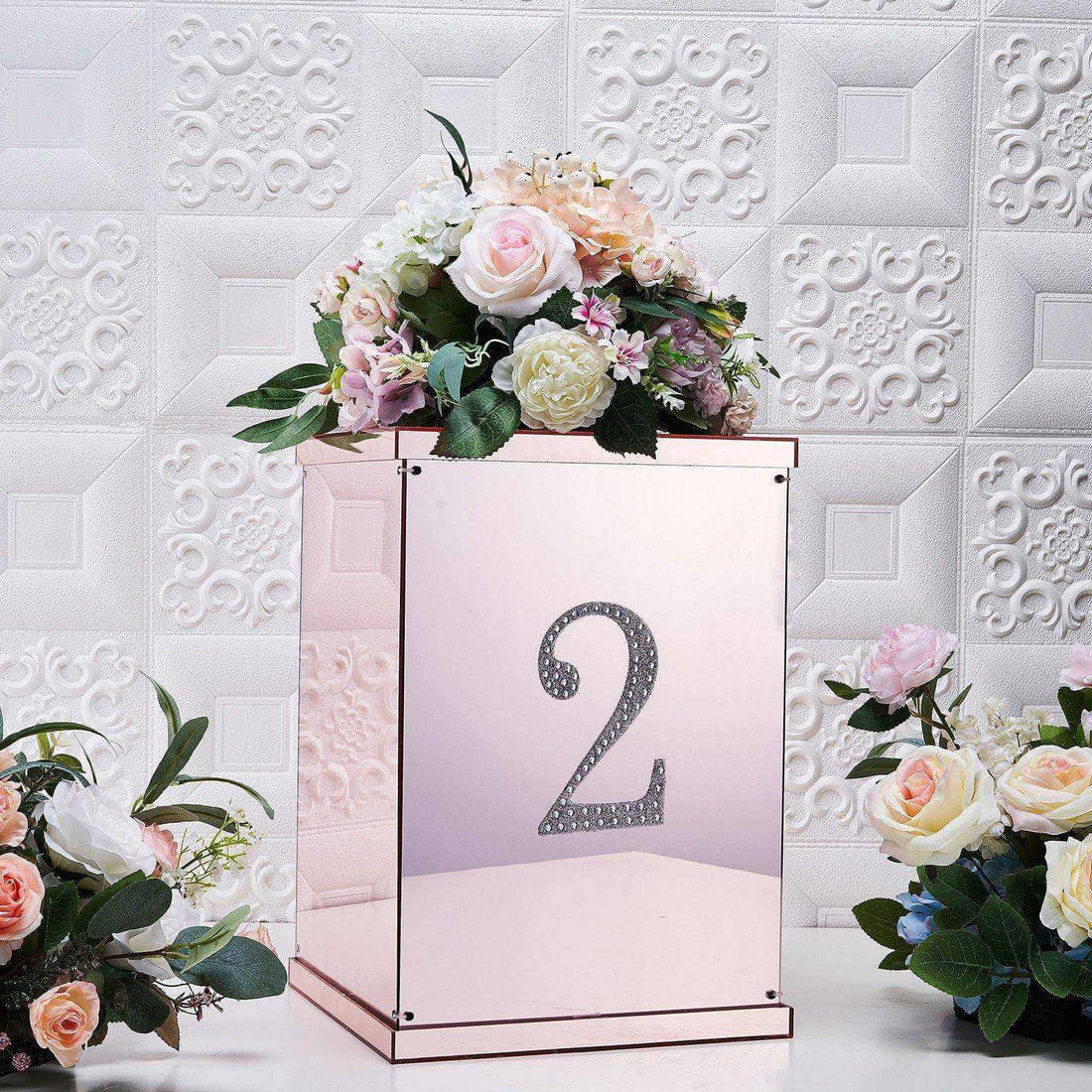 Decorative mirrored box with floral arrangement and number 2 on a textured background.