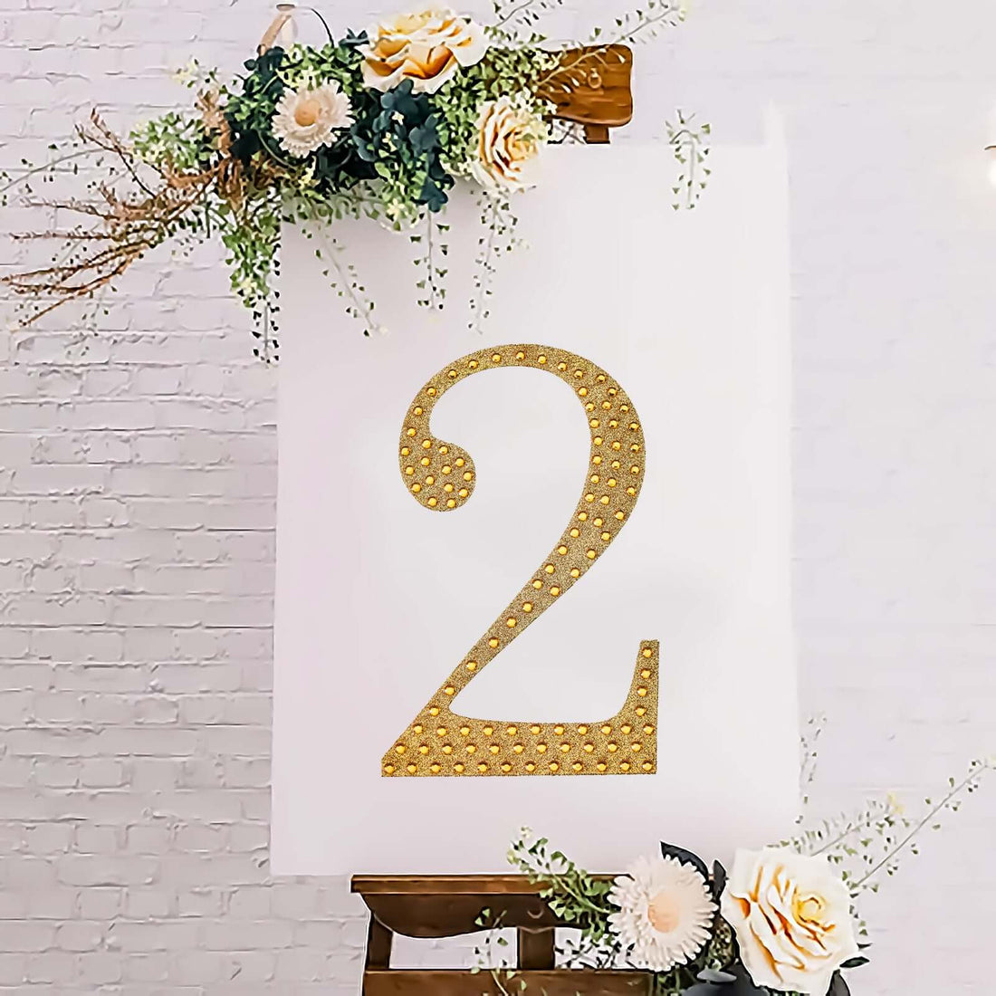 Gold glitter number 2 on a white backdrop with floral accents.