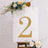 Gold glitter number 2 on a white backdrop with floral accents.