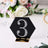 Black hexagon table number 3 with rhinestones on a decorative table setting.