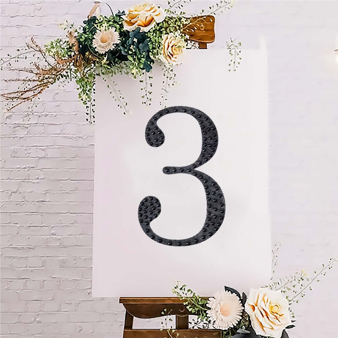 Decorative number three on an easel with floral accents.