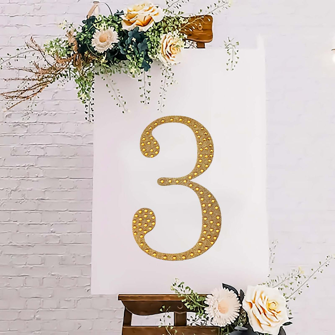 Gold glitter number three on a white backdrop with floral accents.
