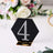 Black hexagonal table number 4 with rhinestones on a gold stand.