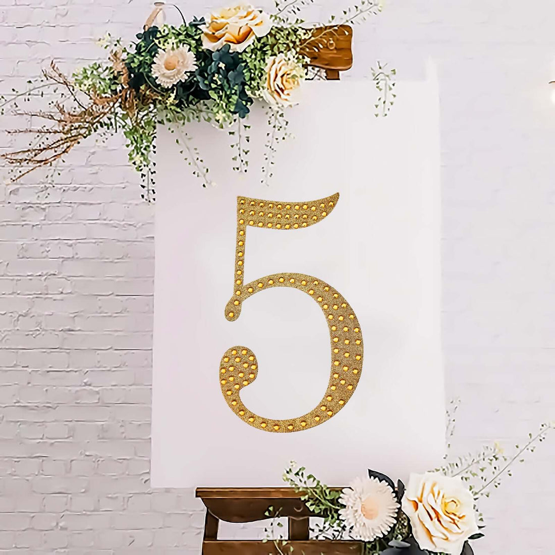 Gold rhinestone number 5 on a white backdrop with floral accents.