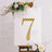 Gold rhinestone number 7 on a decorative sign with floral accents.