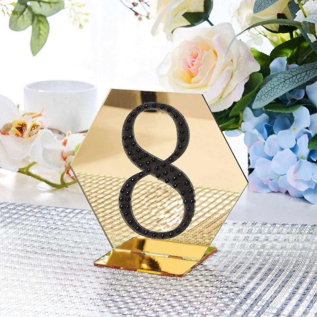 Gold hexagonal table number 8 with black embellishments on a reflective base.