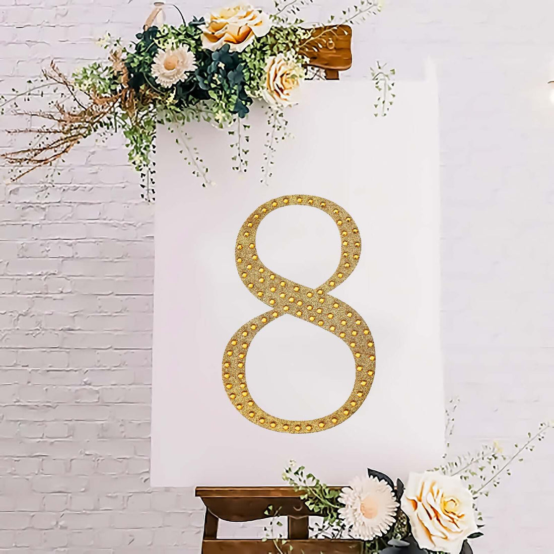 Gold rhinestone number 8 on a white display with floral accents.