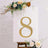 Gold rhinestone number 8 on a white display with floral accents.