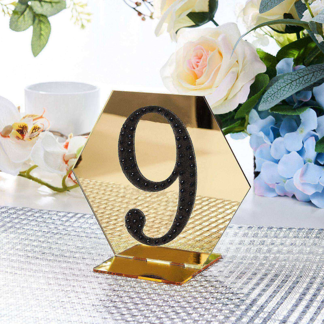 Gold hexagonal table number 9 with rhinestones on a decorative table setting.