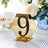 Gold hexagonal table number 9 with rhinestones on a decorative table setting.