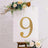 Gold marquee number 9 on a white backdrop with floral accents.