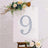 Decorative number 9 with lights on a canvas surrounded by flowers.