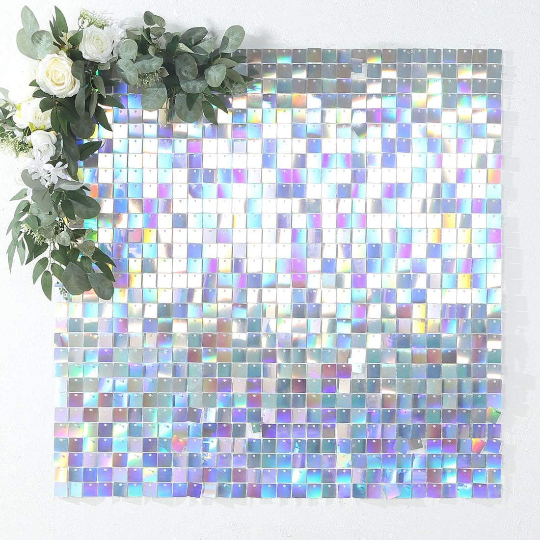 Holographic square tiles arranged in a shimmering pattern with greenery accents.