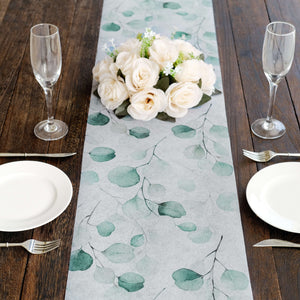 Floral table runner with green leaves on a rustic wooden table setting.