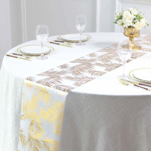 Elegant palm leaf table runner in gold and bronze on a dining table setting.