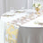 Elegant palm leaf table runner in gold and bronze on a dining table setting.