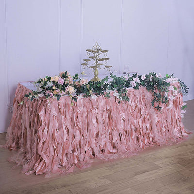 Pink ruffled table skirt adorned with flowers for events and decorations.