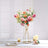 Artificial floral arrangement in a modern gold stand on a dining table.