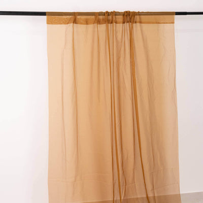 Sheer beige curtain with decorative top trim on a plain backdrop