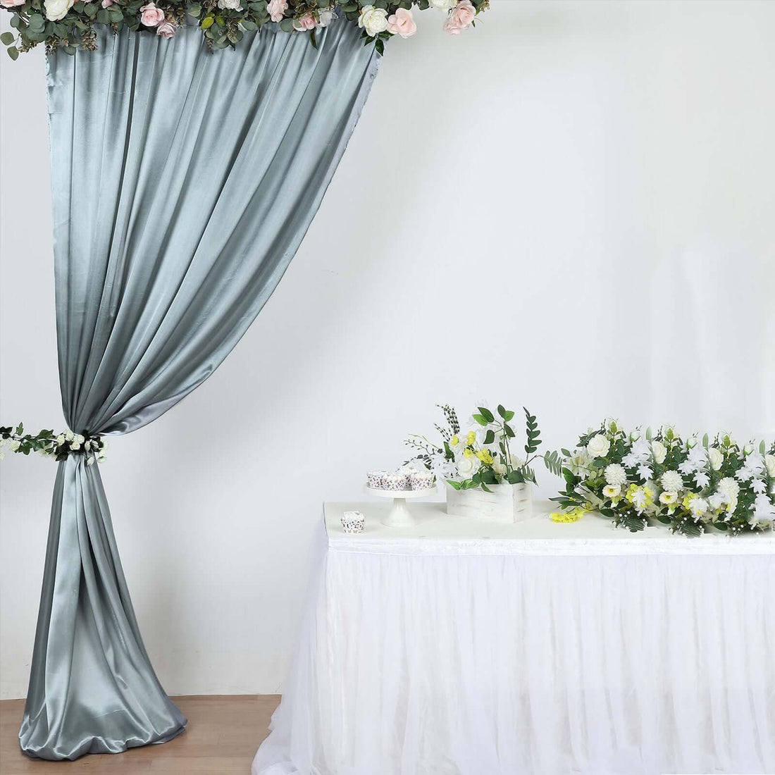Elegant gray drapery with floral accents above a decorated table.