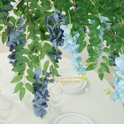 Artificial floral arrangement with blue and green leaves for table decor.