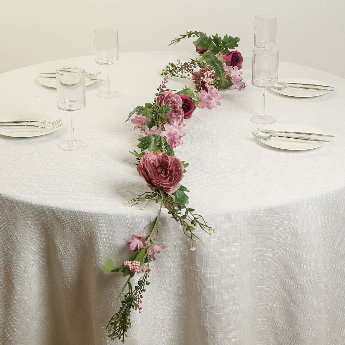 Floral table centerpiece with pink and purple blooms on a dining table.