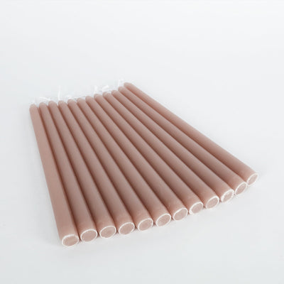 Set of 12 blush taper candles in a studio-style isolation shot.