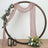 Decorative circular frame with draped fabric and floral arrangements.