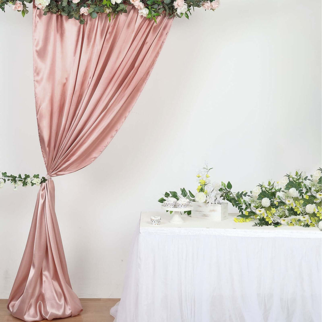 Elegant pink satin curtain with floral decor for event styling.