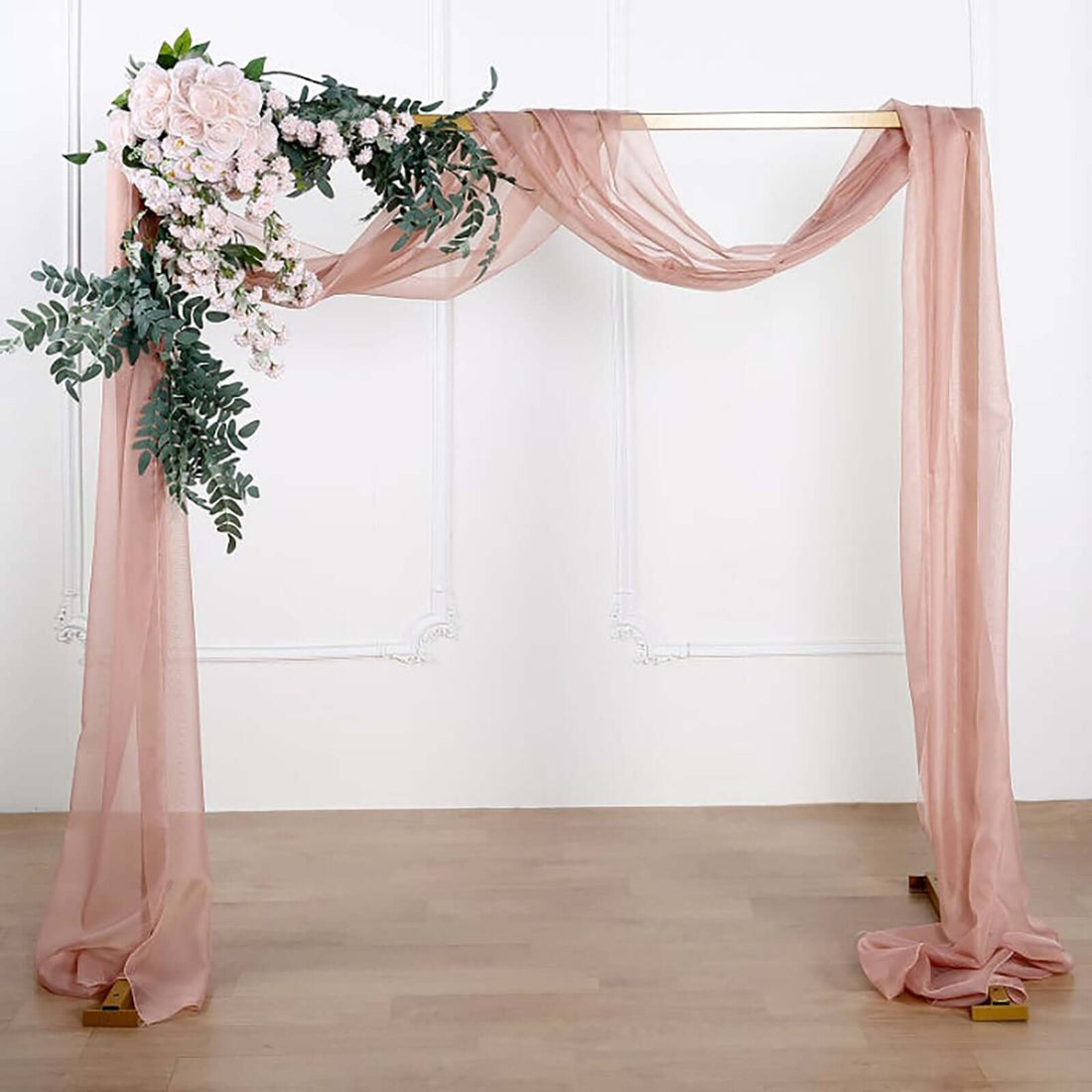 Elegant wedding arch draped in soft fabric with floral accents.