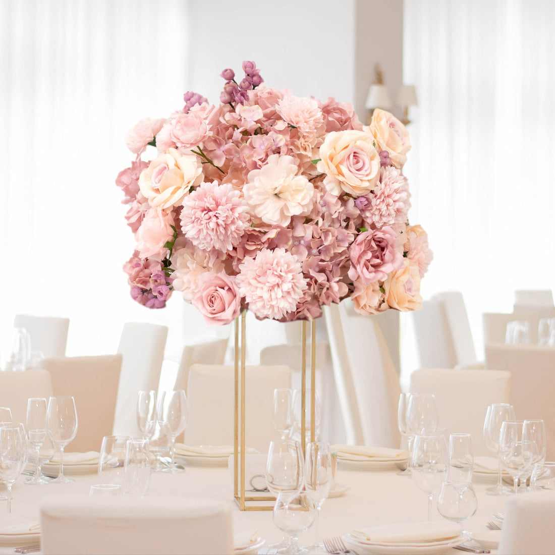 Elegant pink floral centerpiece on a dining table in a bright venue.