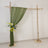 Green drapery backdrop with floral arrangement on a wooden frame.