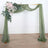 Wedding arch with greenery and pink flowers, draped in sheer fabric.