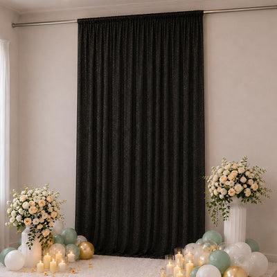 Elegant black curtain backdrop with floral arrangements and pastel balloons