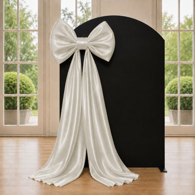 Elegant black gift backdrop with white satin bow and draped fabric gift display