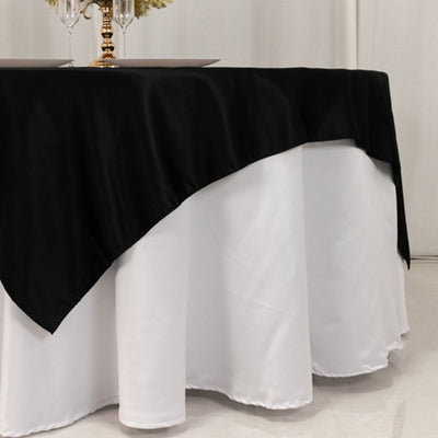 Black tablecloth draped over a round white table in a dining setup.