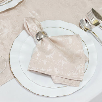 Elegant blush napkin with silver ring on white gold-rimmed dinner plate