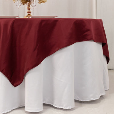 Elegant burgundy tablecloth draped over a round white table.