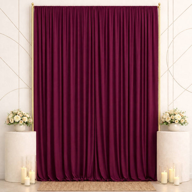 Elegant burgundy velvet backdrop with floral arrangements and candles