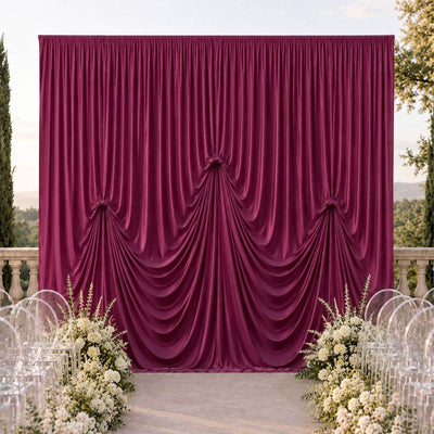 Elegant burgundy wedding backdrop with draped curtains and floral aisle decor